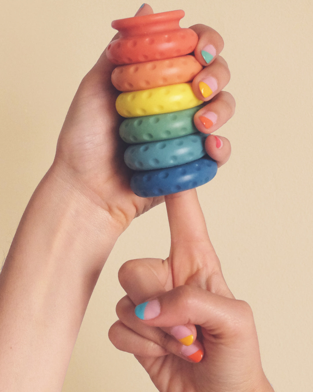 Rainbow Ohnut rings held in model's hand and on finger with rainbow nail polish