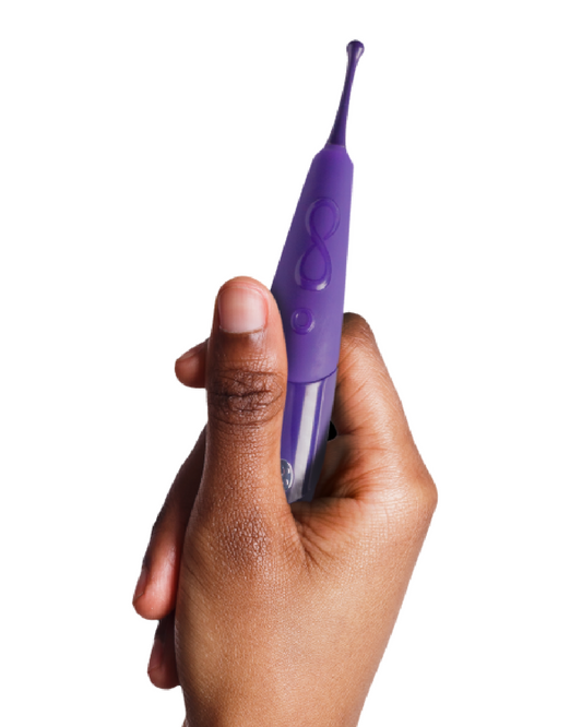 Zumio X Powerful Oscillating Rechargeable Clitoral Stimulator - Purple held in a woman's hand on a white background