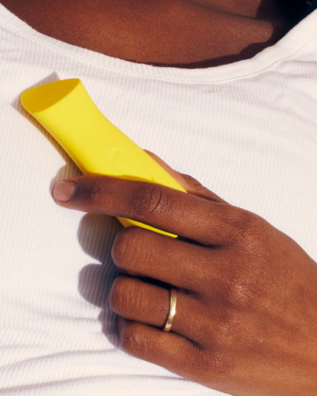 Dame Kip Waterproof Lipstick Vibrator  - Yellow  held in a person's hand against their chest
