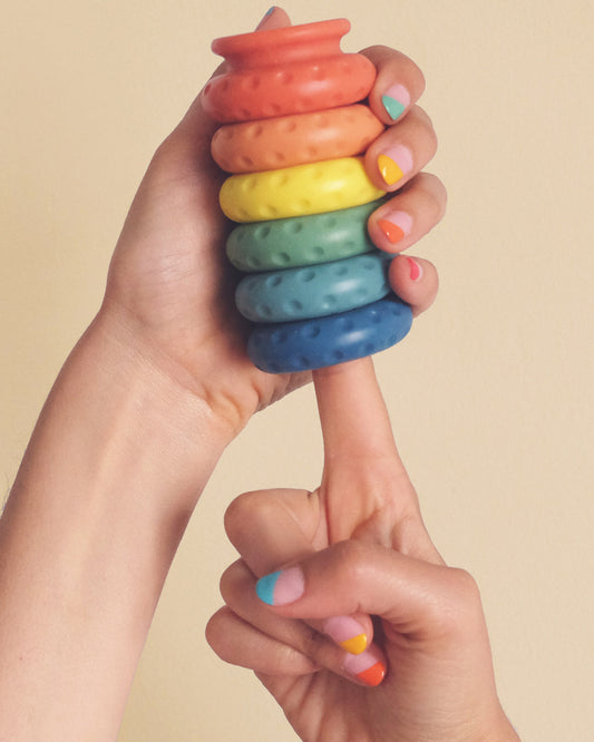 Rainbow Ohnut rings held in model's hand and on finger with rainbow nail polish 