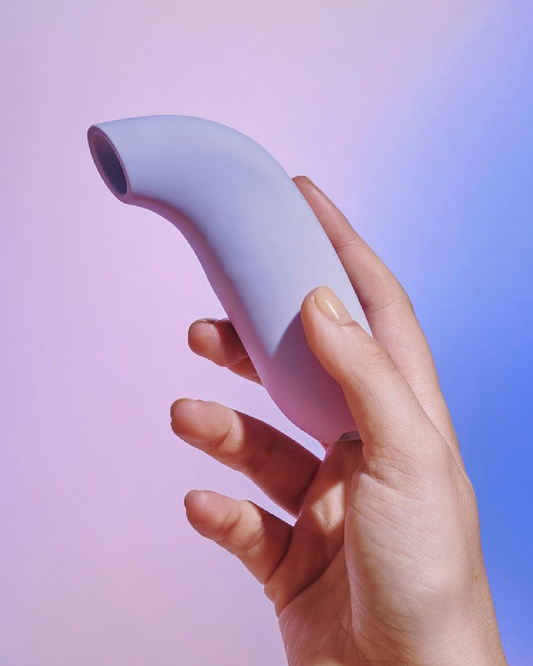 Dame Aer Clitoral Suction Vibrator  held in a hand on a lavender background to show the size